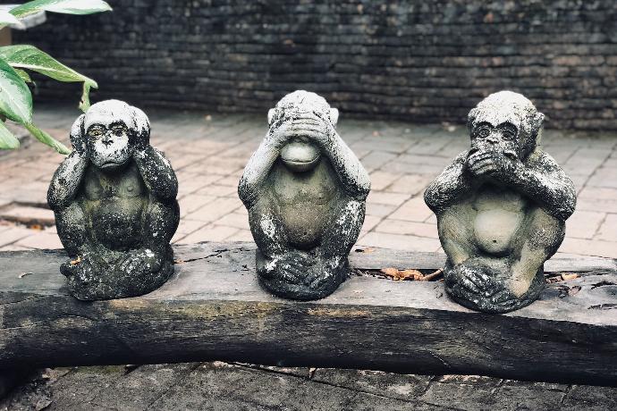 three wise monkeys statuette on log at daytime
